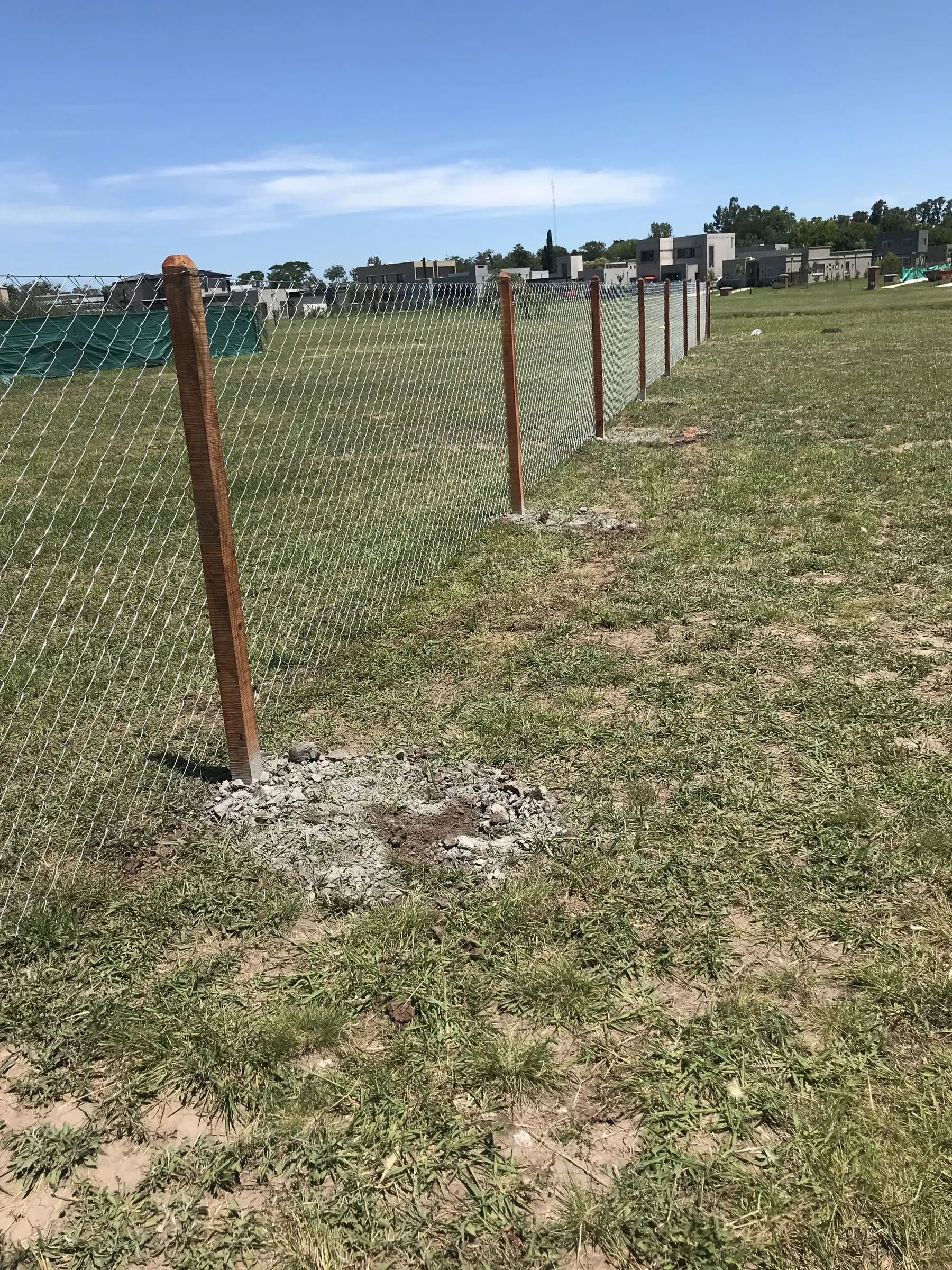 Alambrado de tejido romboidal con postes de hormigón sobre un lote con césped